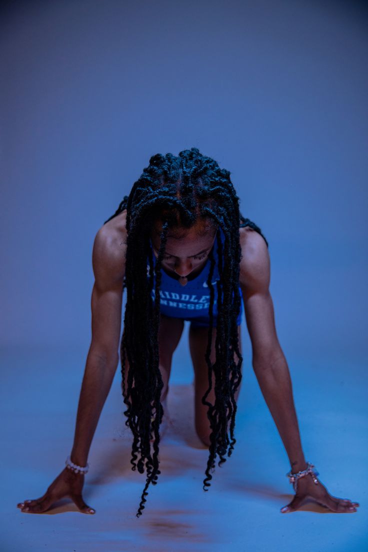 a woman with dreadlocks bending over on her knees