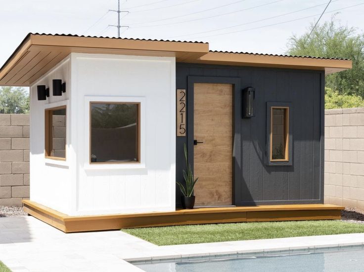 a small white and black shed next to a pool