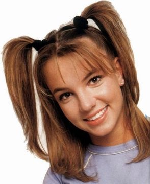 a woman with her hair in a ponytail smiling at the camera while wearing a blue t - shirt