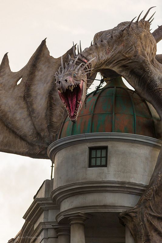 a dragon statue on top of a building with its mouth open and it's tongue out