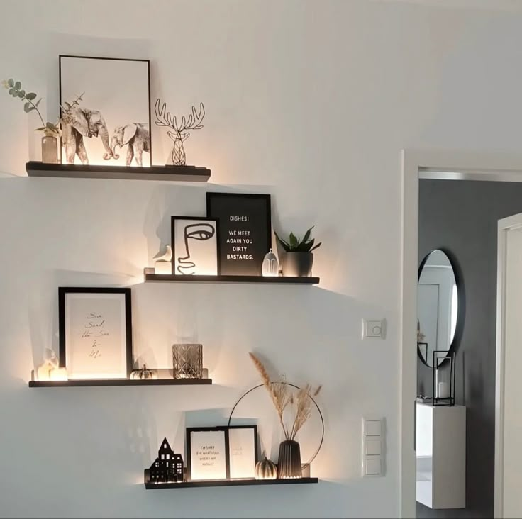 some shelves with pictures and candles on them in a room that is decorated with white walls