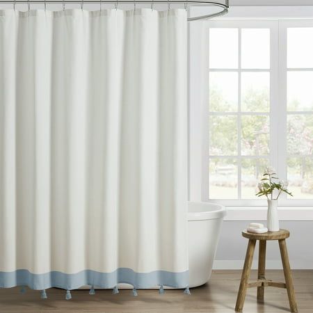 a white and blue shower curtain next to a bathtub in a room with wooden floors