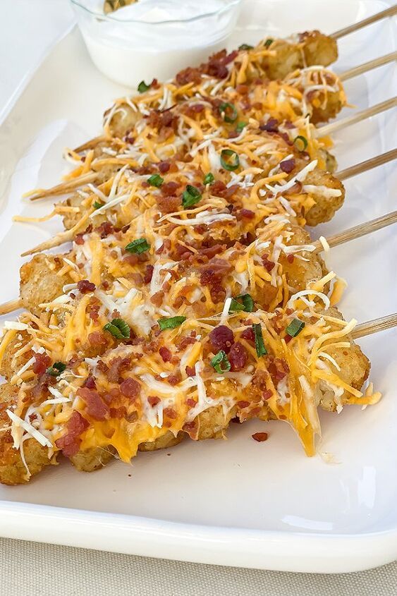 several pieces of pizza with cheese and toppings on skewers sitting on a white plate