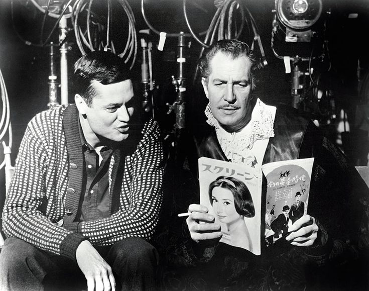 black and white photograph of two men sitting next to each other, one reading a book