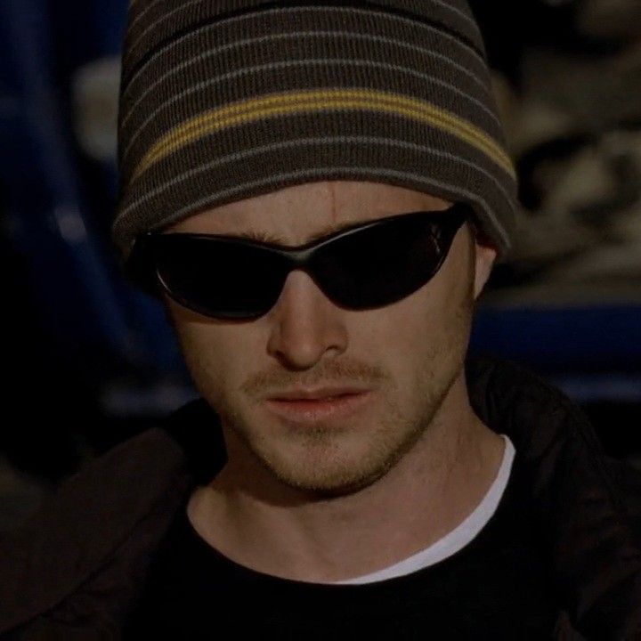 a man wearing sunglasses and a beanie looks off to the side in front of him