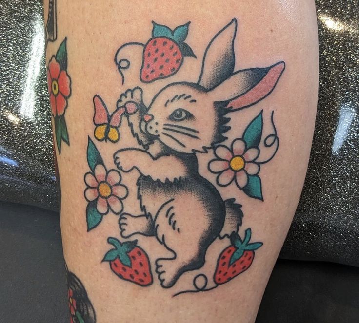 a rabbit with flowers and strawberries on it's leg