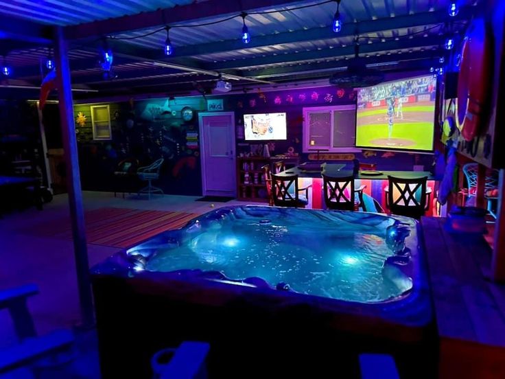 an indoor hot tub in the middle of a room with several televisions and tables