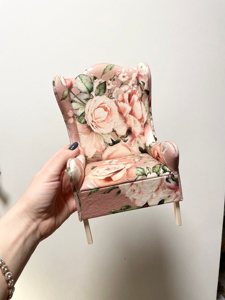 a hand holding a miniature chair with flowers on it