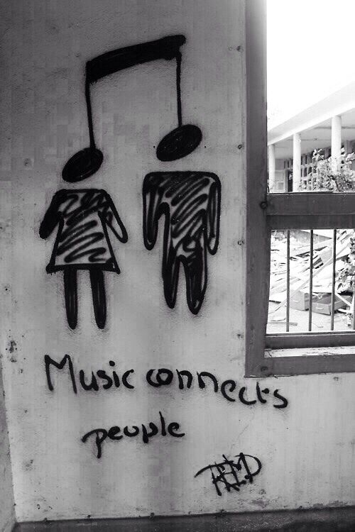 graffiti on the side of a building with music notes and people's faces painted on it