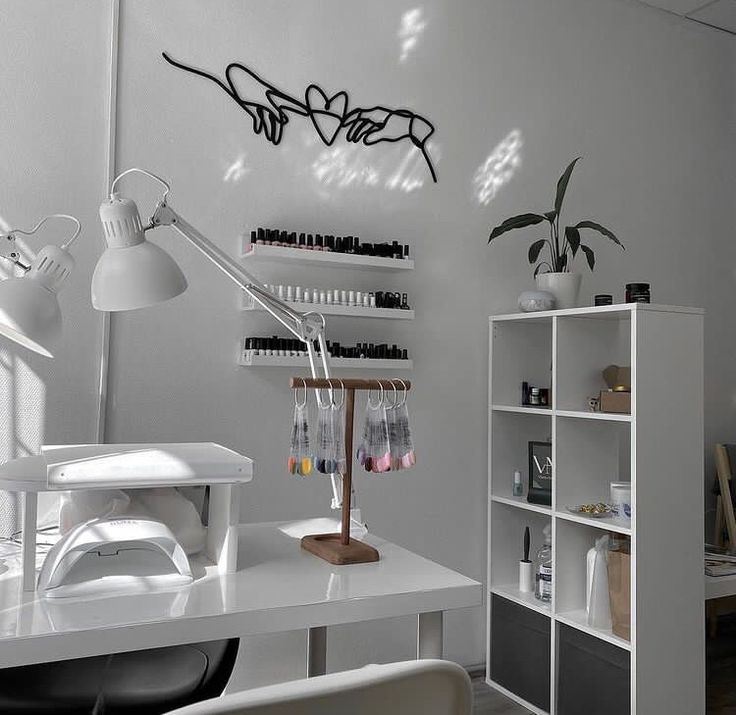 a white desk topped with a lamp next to a book shelf filled with lots of books