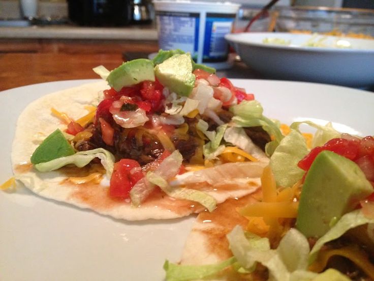 two tortillas on a plate with lettuce, tomatoes and other toppings