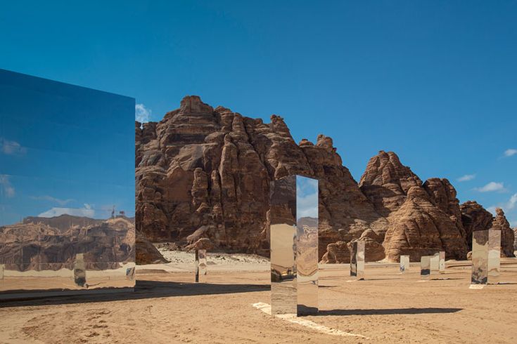 several mirrors are placed in the middle of a desert area with mountains and rocks behind them