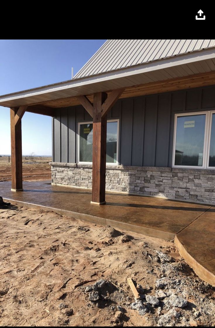 a house that is under construction with some rocks on the ground and a porch attached to it