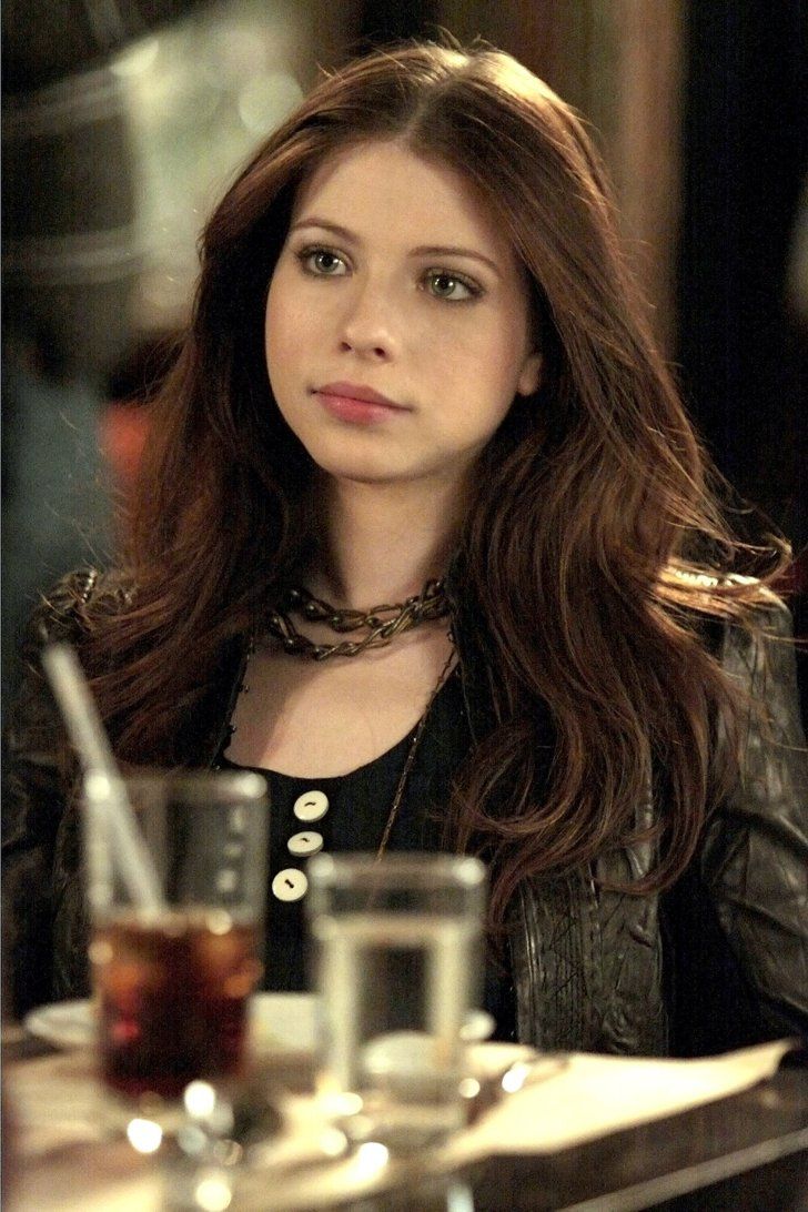 a woman sitting at a table with drinks in front of her and looking off to the side