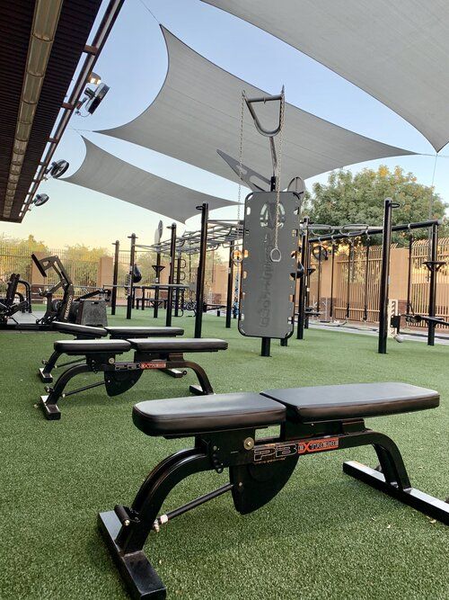 an empty gym with benches and equipment on the grass in front of some large white awnings