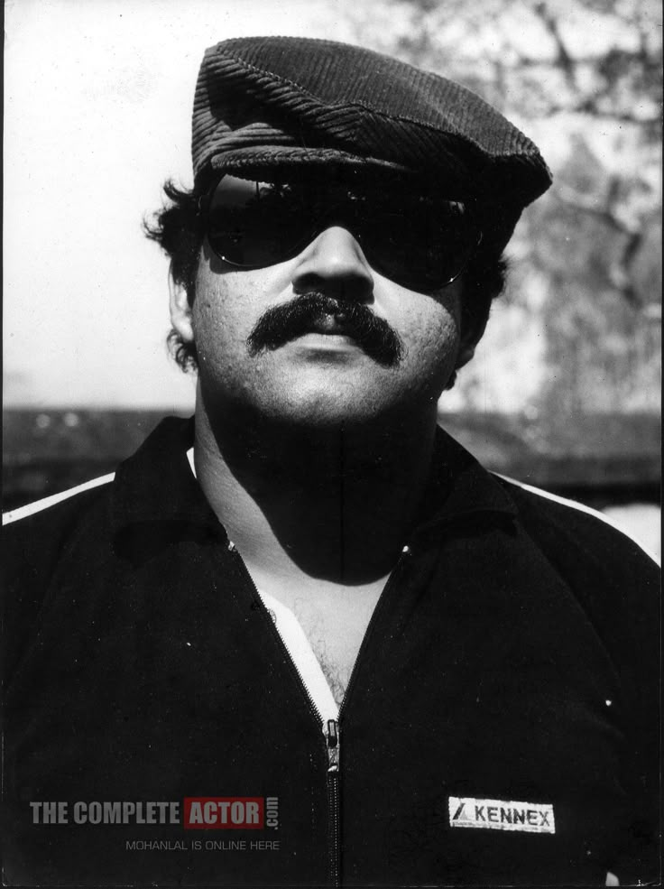 a black and white photo of a man with sunglasses on his face wearing a hat