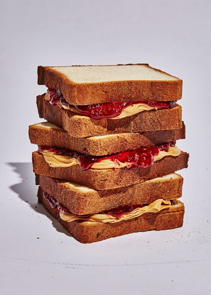 three sandwiches stacked on top of each other with jelly and peanut butter spread on them