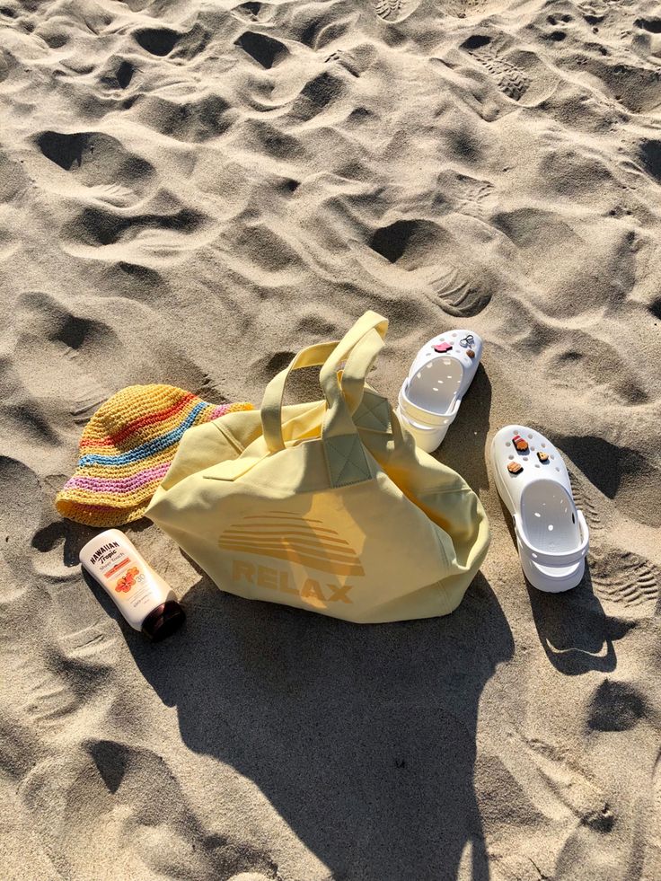 a towel, flip flops and sun hat lay on the sand