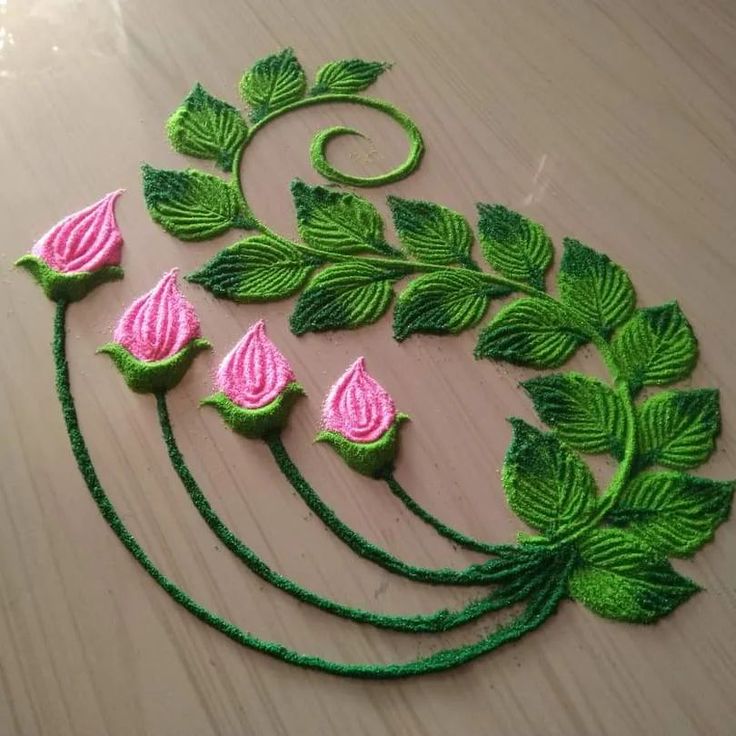 some green and pink crocheted flowers on top of a wooden table with leaves