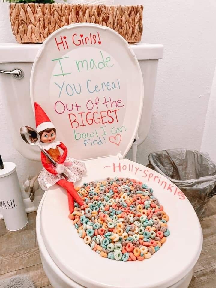 an elf is sitting on top of a toilet with cereal in the bowl and writing on the lid