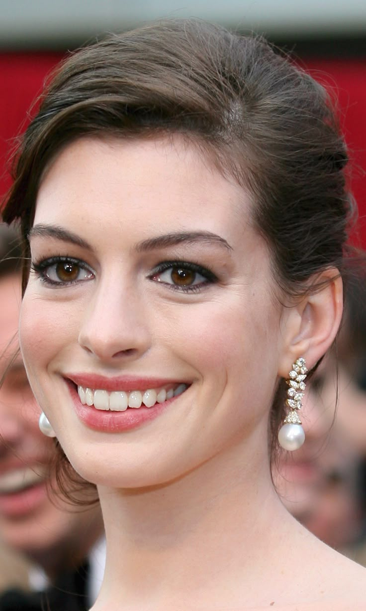 a close up of a person with a smile on their face and wearing pearls in her hair