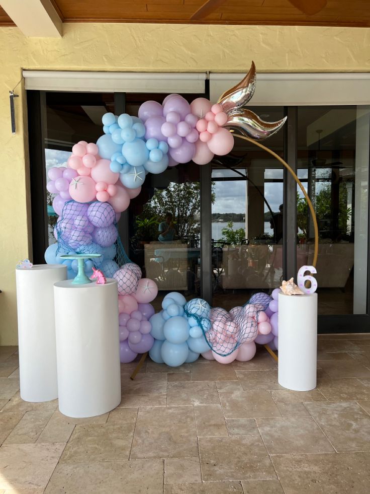 a balloon arch is decorated with mermaid balloons