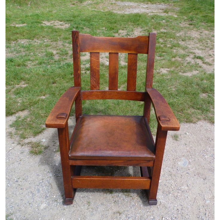 a wooden chair sitting on top of a grass covered field