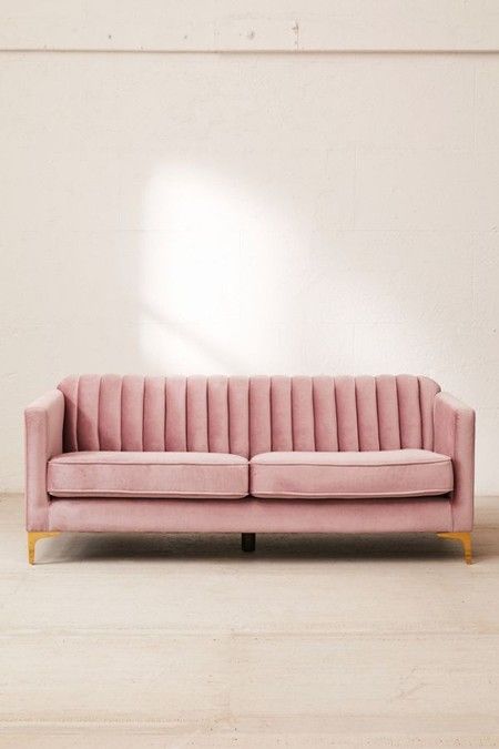 a pink velvet couch against a white wall