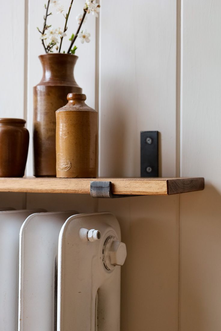 a shelf with some vases on top of it and two radiators next to it