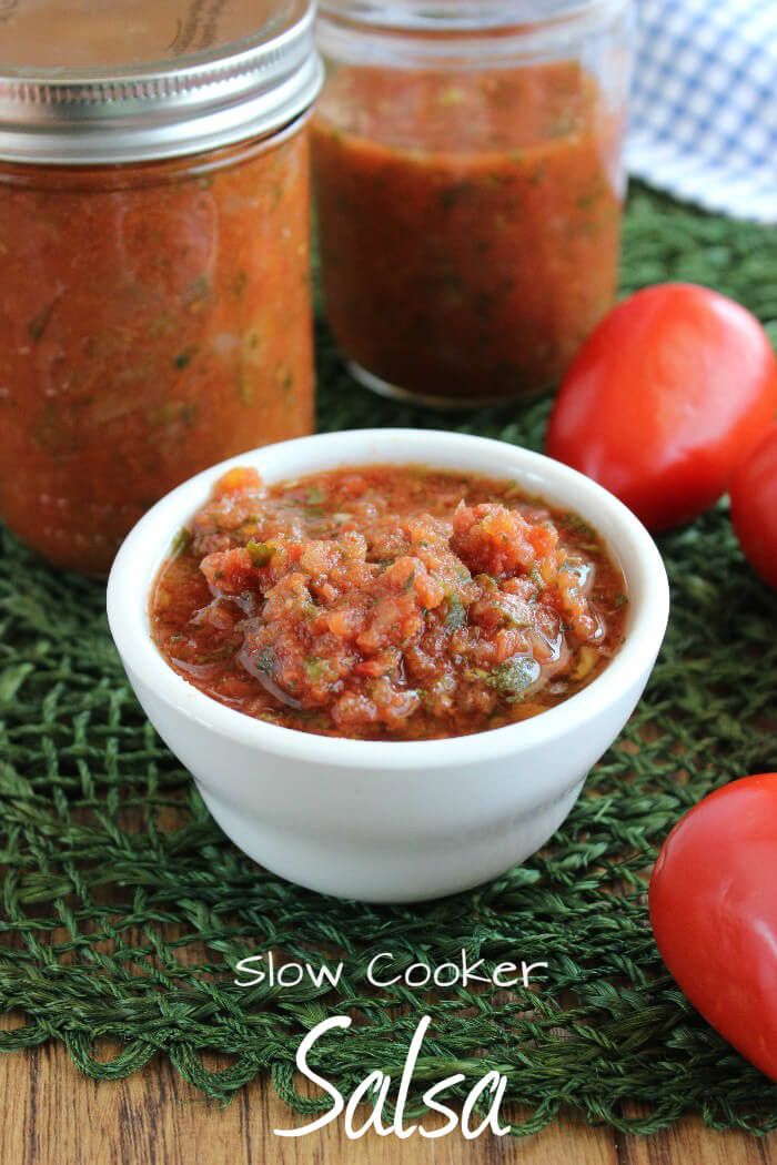 slow cooker salsa in a small white bowl with tomatoes around it on a green mat