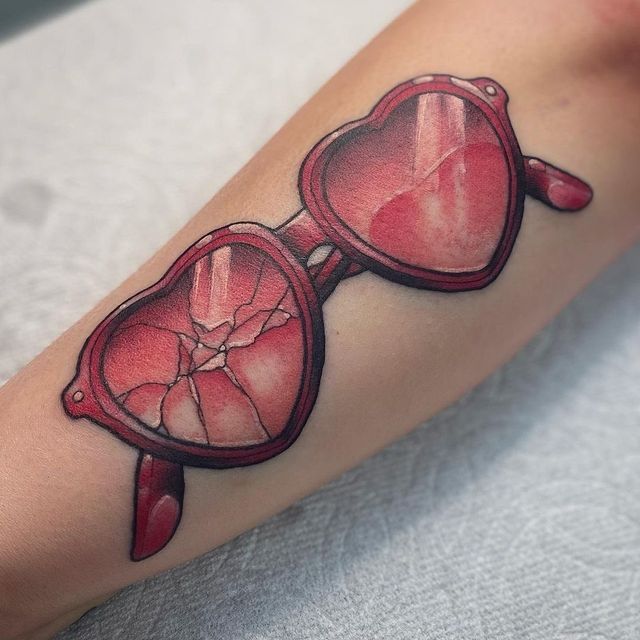 a woman's arm with a tattoo on it that has red glasses in the shape of a heart