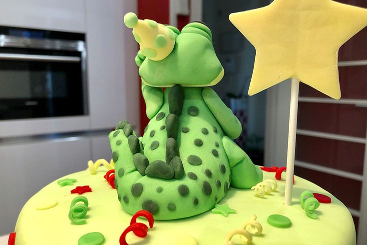 there is a green cake with stars on the top and decorations in the shape of animals