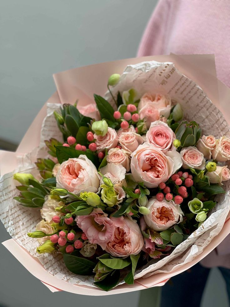 a person holding a bouquet of flowers in their hands with pink and green foliage on them