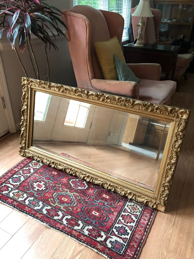 a large mirror sitting on top of a wooden floor next to a chair and rug