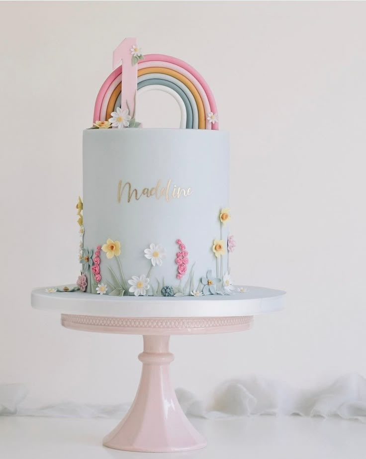 a blue cake with flowers and rainbows on top