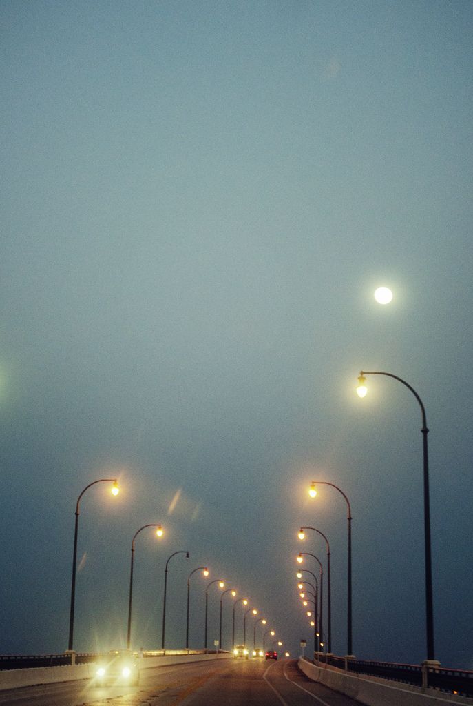 an empty road with street lights on both sides and fog in the air above it