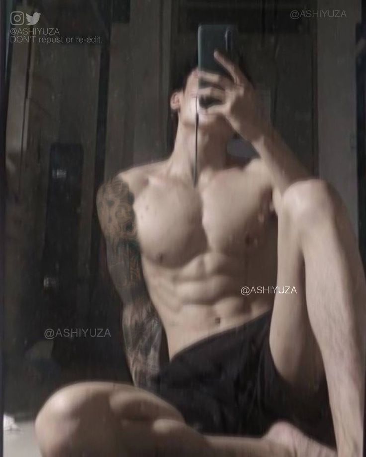 a shirtless man taking a selfie in front of a mirror with his cell phone