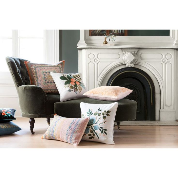 a living room filled with lots of pillows on top of a green chair next to a fire place