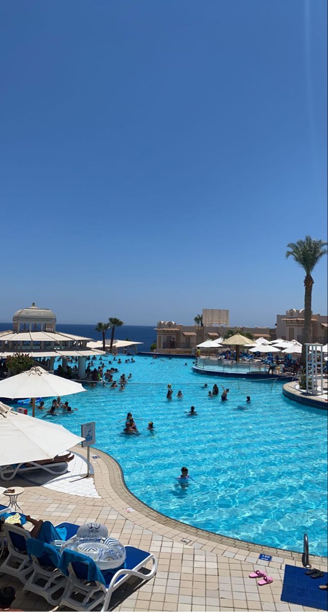 people are swimming in an outdoor pool near the ocean