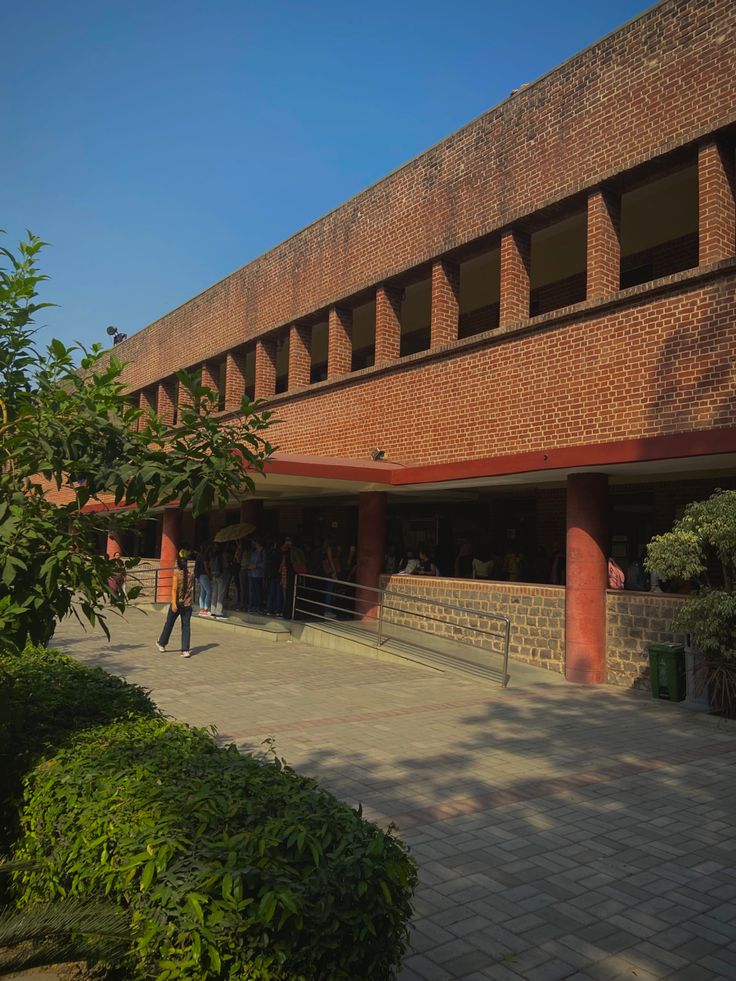 people are walking around in front of a building that has red brick walls and arches