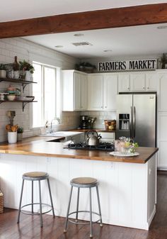 a kitchen with two stools in front of the island and an open floor plan