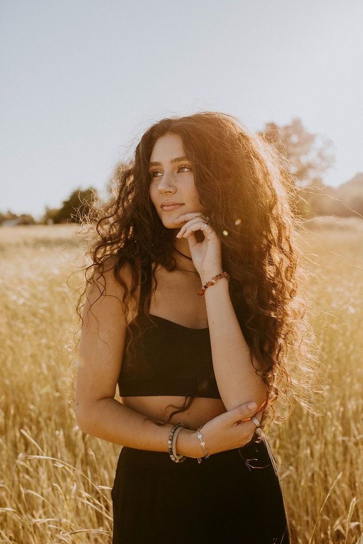 a woman standing in a field with her hands on her chin