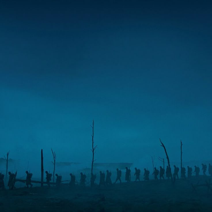 a group of people standing on top of a field under a blue sky at night