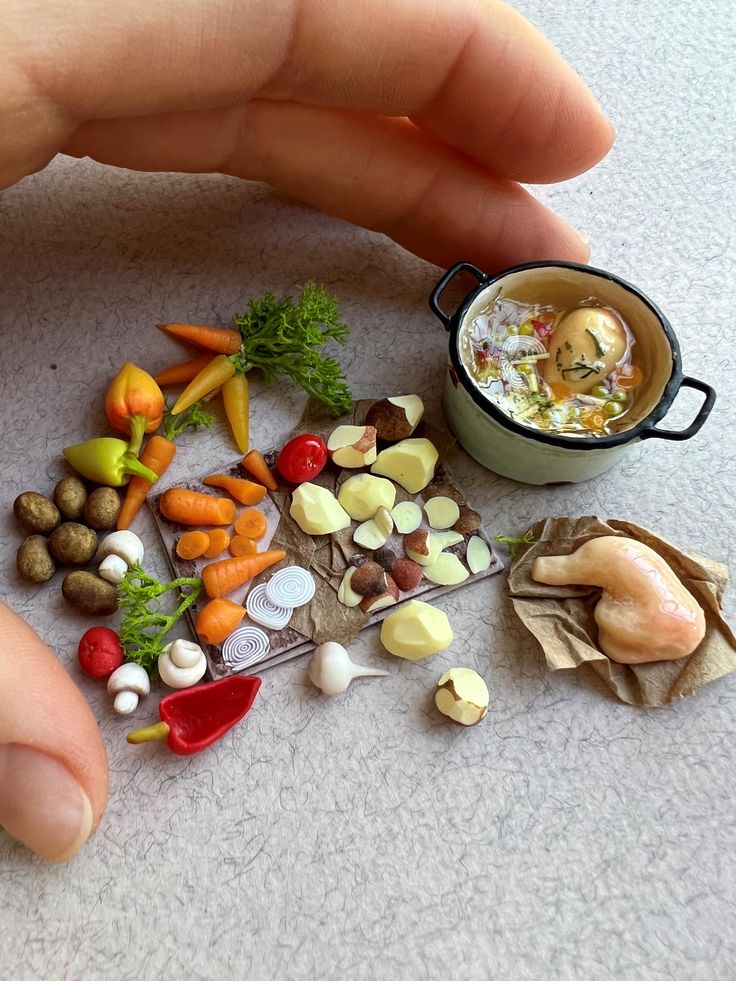 a hand is reaching for food on the floor next to a miniature cup and saucer