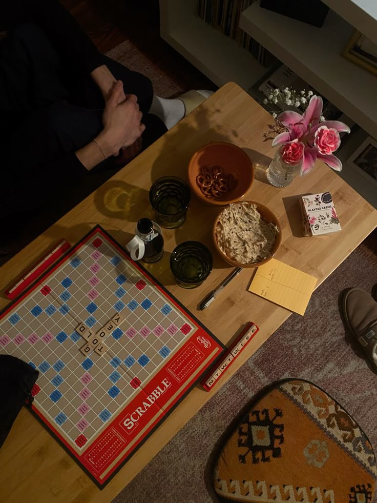 a board game sitting on top of a wooden table next to a vase with flowers