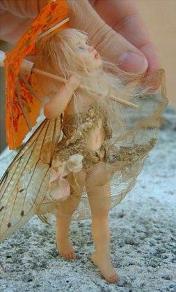 a hand is holding a doll with wings