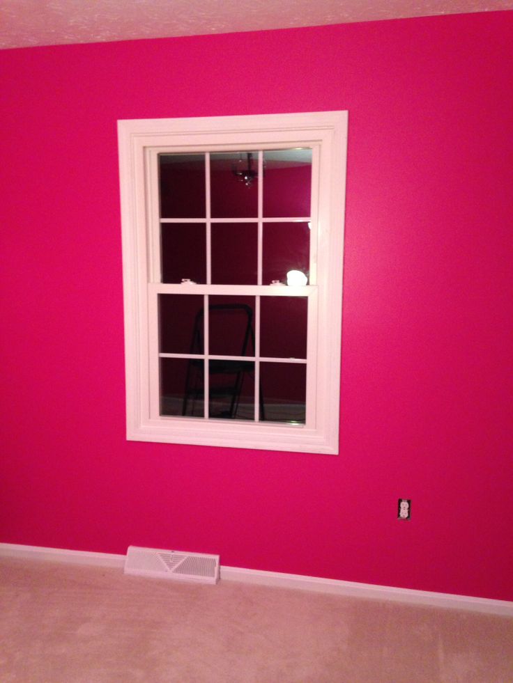 an empty room with pink walls and a window in the center, white trim on the windowsill