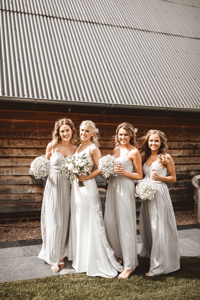 the bride and her bridesmaids pose for a photo in front of an old barn