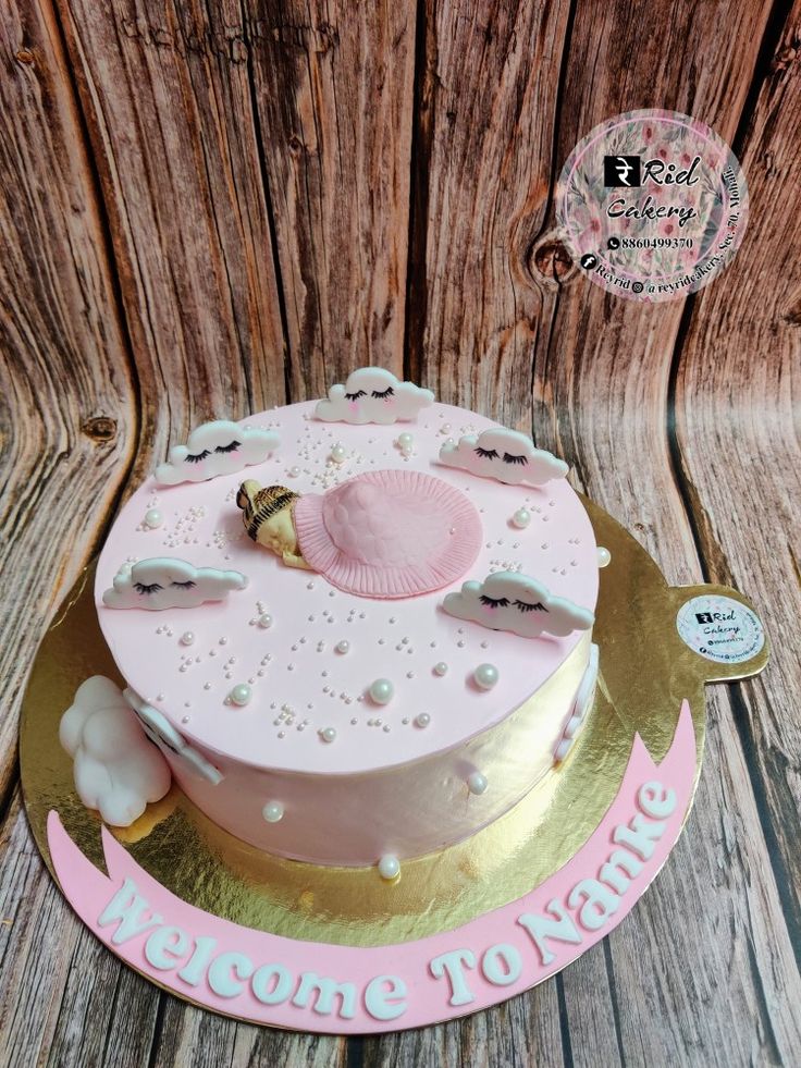 a pink and gold birthday cake sitting on top of a wooden table