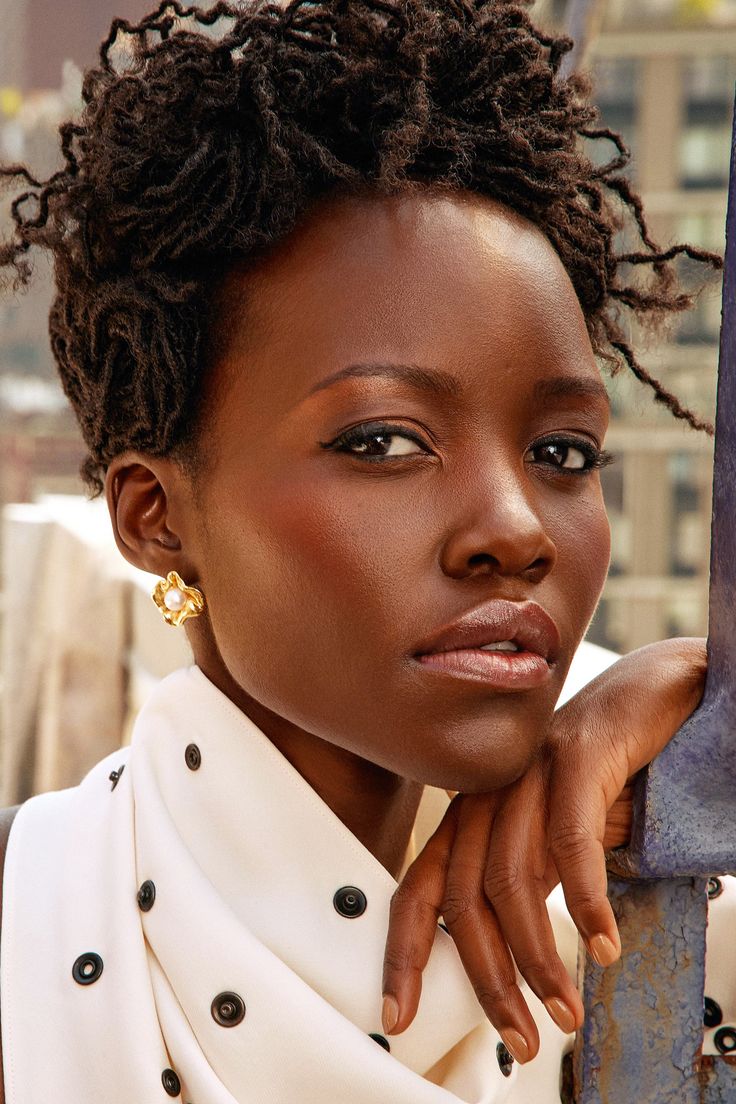 a woman with short hair leaning against a pole